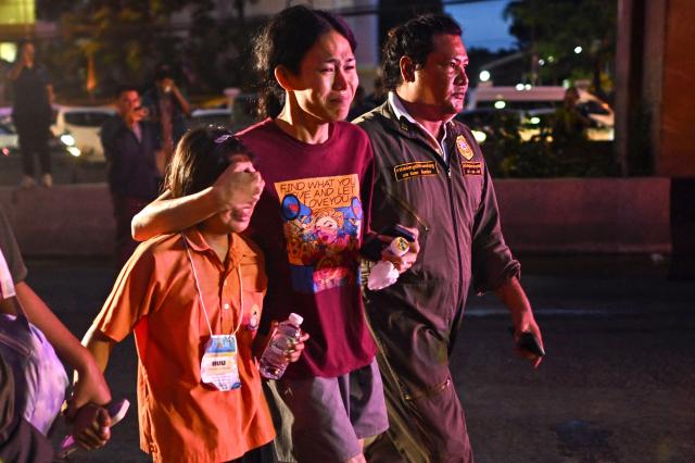 Relative shields childs eyes from burned bus wreckage after fatal Thai school trip fire that killed up to 25 on October 1 2024 AFP-Yonhap