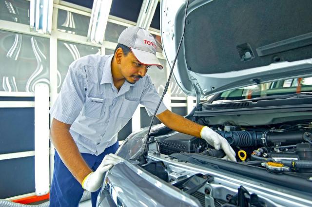 A repairman wearing a Toyota hat inspects a vehicle Captured from UMW Toyota Motor website