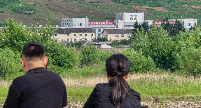 Chinese tourists observe North Koreas Namyang Station area located in Onsong County just across the China-North Korea border featuring large portraits of Kim Il-sung and Kim Jong-il from a riverside park along the Tumen River in Tumen City Yanbian Korean Autonomous Prefecture Jilin Province on June 12 AJP dbeorlf123ajunewscom