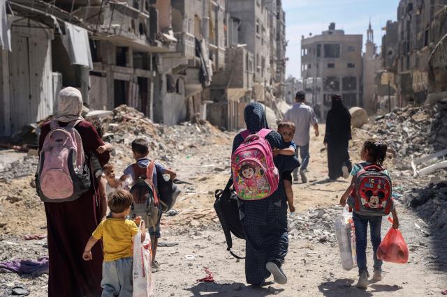 This photo shows Palestinian women and their children walking through ruins scarred by the ongoing conflict between Israel and Palestine May 31 2024 AP-Yonhap