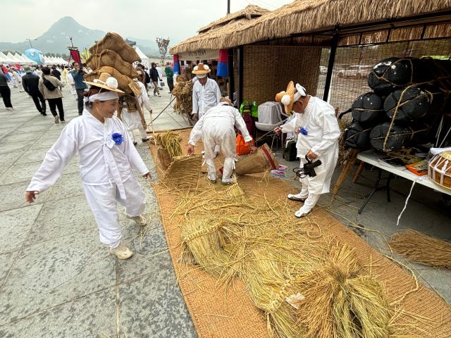 People dressed in traditional costumes make straw crafts at the Wow Festival in Gwanghwamun Plaza Seoul on Oct 15 2024 AJP Han Jun-gu