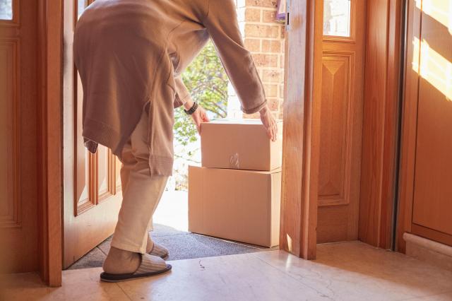 This photo shows a woman receiving a package. Getty Images Bank