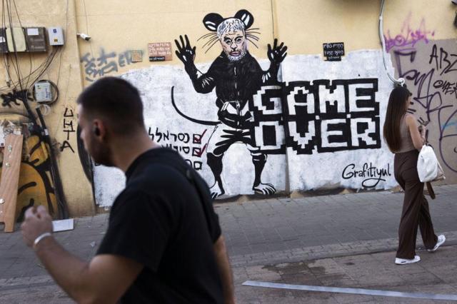 People pass by a newly painted graffiti depicting Hamas Leader Yahya Sinwar days after he was killed by Israeli forces in Gaza in Tel Aviv Israel on Oct 20 2024 AP-Yonhap