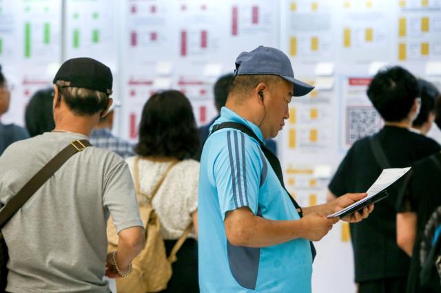 Middle aged workers browsing job posts at a fair AJP Dong-woo Kim