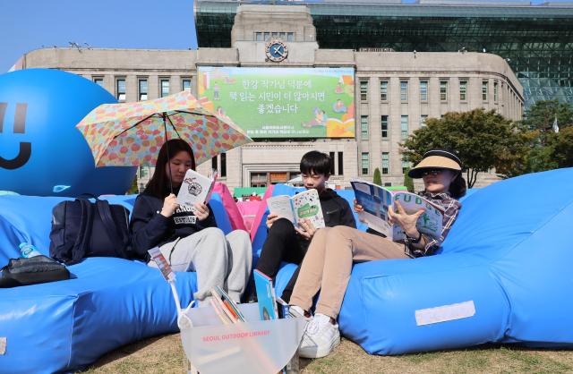 지난 17일 서울도서관 앞 서울광장에서 한 가족이 책을 읽고 있다 사진연합뉴스