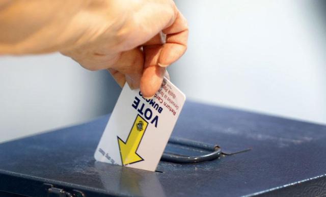 A voter deposits a voting card into a ballot box during the first day of early voting at the Galleria at Sunset mall in Henderson Nevada on Oct 19 2024 AP-Yonhap