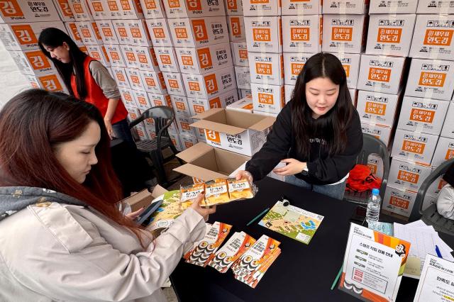 A staff member distributes seaweed sheets to participants at the World Gimbap Festival 2024 at Yeouido Hangang Park in Seoul on Nov 1 2024 AJP Kim Dong-woo