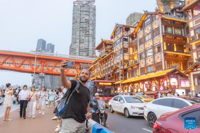 A tourist from Pakistan snaps a selfie at the Hongyadong scenic area in Chongqing’s Yuzhong district southwest China on July 8 2024 Xinhua-Yonhap 