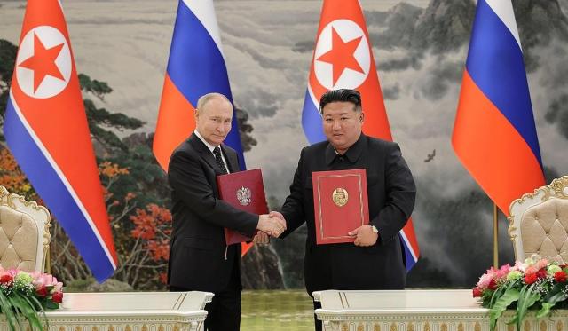 Russian President Vladimir Putin left and North Korean leader Kim Jong-un right shake hands signed after a summit held in Pyongyang on June 19 2024 Yonhap