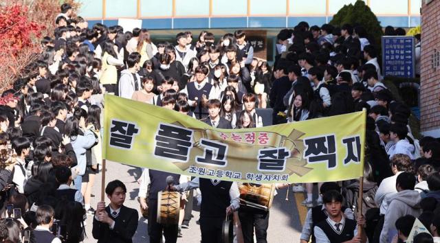 Students cheer for their seniors taking the annual university entrance exam at a high school in Gyeonggi Province