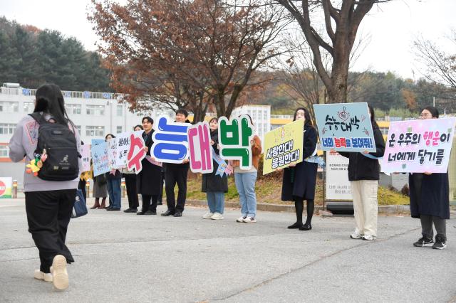 화천군청 교육청 학부모 후배들이 이른 아침부터 화천고교 고사장에 입실하는 수험생들에게 수능 만점을 기원하는 응원을 하고 있다