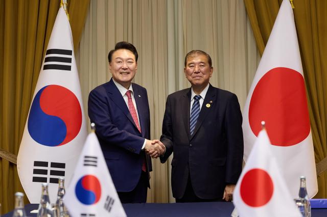 South Korean President Yoon Suk Yeol left shakes hands with Japanese Prime Minister Shigeru Ishiba during their summit in Lima on Nov 16 2024 Yonhap