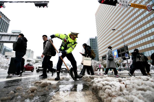 A police officer removes snow from a crosswalk in Seoul on Nov 27 2024 AJP Kim Dong-woo