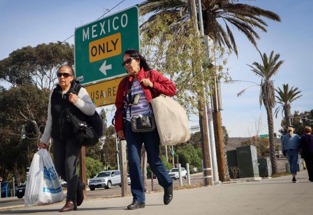 Shoppers walk with their purchases near the US-Mexico border in San Ysidro California Nov 26 2024 AFP-Yonhap