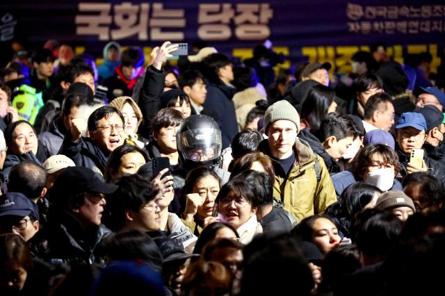 Citizens gathered in front of the National Assembly building in Yeouido cheer moments after the resolution to lift martial law was passed at about 100 am on Dec 4 AJP Kim Dong-woo