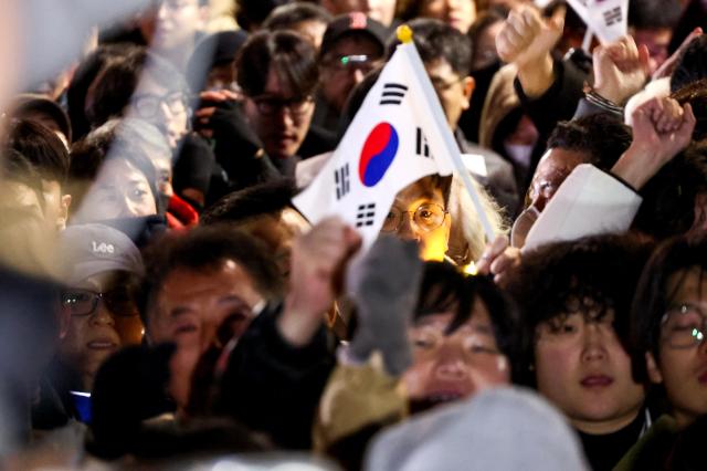 Citizens gathered in front of the National Assembly building in Yeouido cheer moments after the resolution to lift martial law was passed at about 100 am on Dec 4 AJP Kim Dong-woo