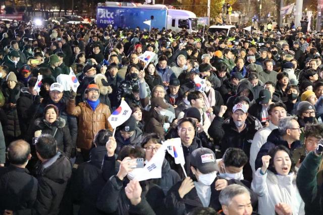 Citizens gathered in front of the National Assembly building in Yeouido cheer moments after the resolution to lift martial law was passed at about 100 am on Dec 4 AJP Han Jun-gu