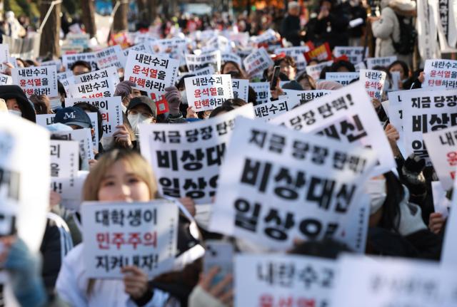  7일 오후 서울 영등포구 여의도 산업은행 본점 인근에서 열린 에서 대학생들이 비상계엄을 선포한 대통령의 퇴진을 촉구하며 손팻말을 흔들고 있다 사진연합뉴스