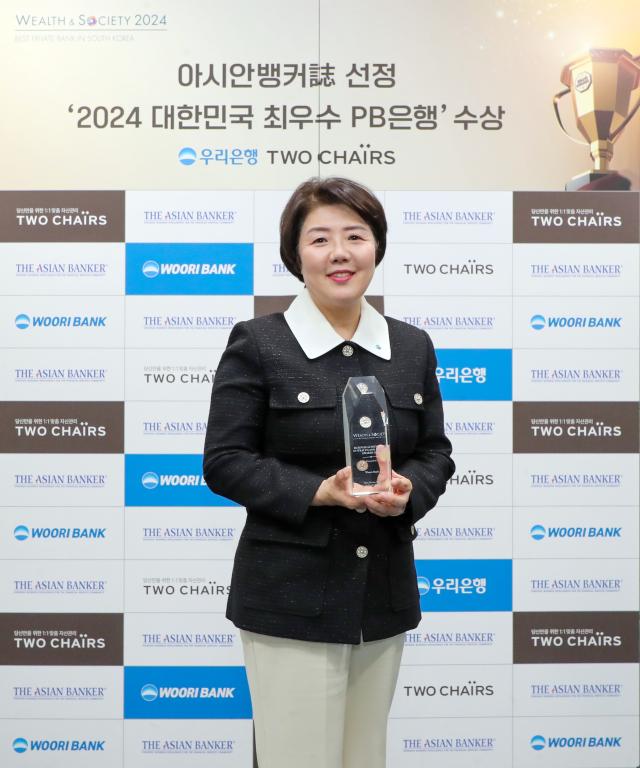 송현주 우리은행 자산관리그룹장이 아시안뱅커가 수여한 글로벌 웰스 앤드 소사이어티 어워즈 수상 트로피를 들고 기념 촬영을 하고 있다 사진우리은행