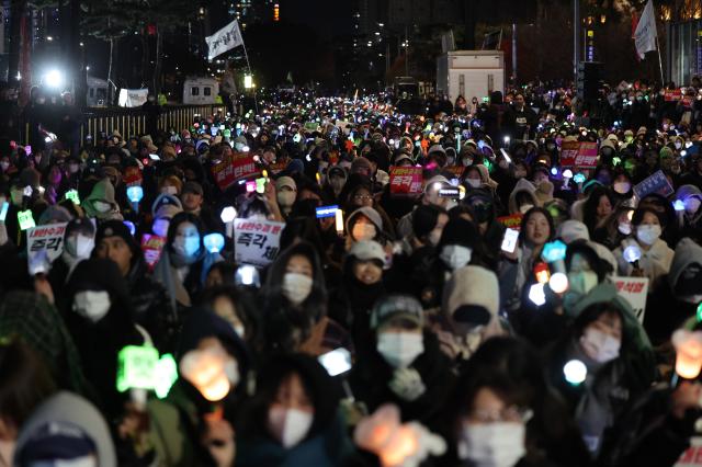 8일 오후 서울 여의도 국회 앞에서 열린 윤석열 탄핵 및 구속을 촉구하는 촛불문화제에서 참가자들이 관련 손팻말과 응원봉을 들고 있다 사진연합뉴스