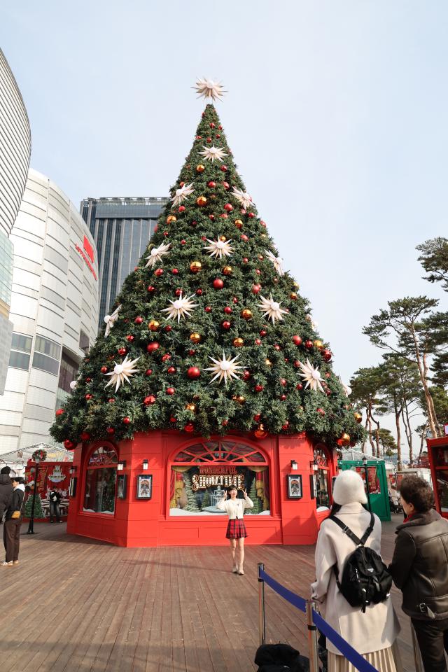 A visitor takes a photo at the Christmas tree in the Christmas market at Jamsil Seoul Dec 13 2024 AJP Han Jun-gu