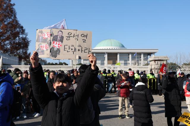 A boy holds a sign that reads Impeach Yoon Suk Yeol outside the National Assembly on Dec 14 2024 AJP Han Jun-gu