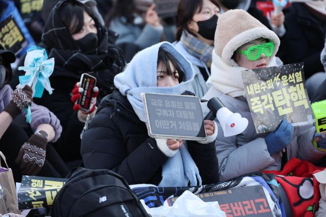 A woman center holds a sign reading President an avid subscriber to extreme-right YouTube channels outside the National Assembly in Seoul on Dec 14 2024 AJP Han Jun-gu