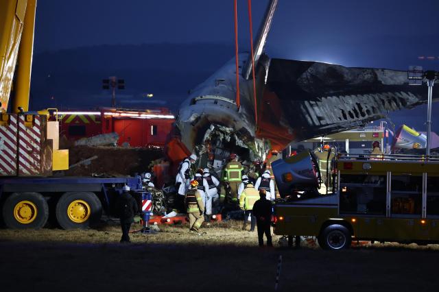 Workers use a crane to move the damaged tail section of a Jeju Air aircraft that crashed and exploded at Muan International Airport in South Koreas southwest region on Dec 29 2024 Yonhap