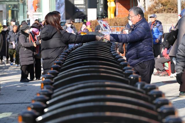 Rally participants distribute Korean national flags and American flags at a rally near the Presidential residence in Hannam-dong Seoul on Jan 2 2025 AJP Han Jun-gu