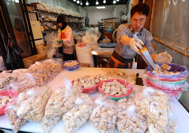 A merchant at a traditional market in Busan makes sweet rice crackers on Jan 17 Yonhap