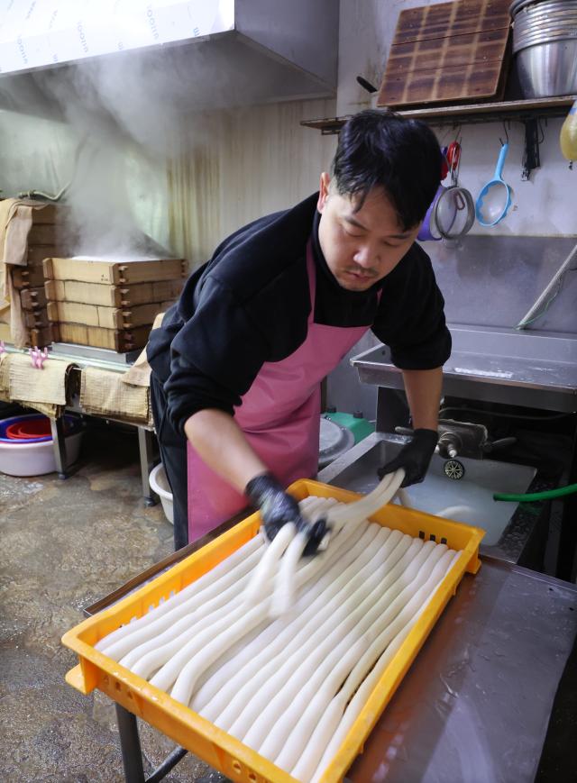 Rice cake makers at a traditional market in Busan on Jan 15 prepare long race cakes garaetteok an ingredient for the traditional rice cake soup tteokguk Yonhap