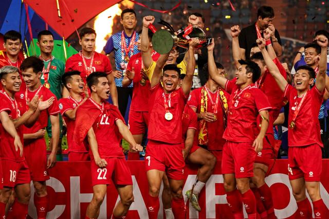 Viet Nams midfielder Xuan Manh Pham center and teammates celebrate with the trophy after winning the 2024 ASEAN Electric Cup final second leg football match between Thailand and Vietnam at the Rajamangala National Stadium in Bangkok on Jan 5 2025 AFP-Yonhap