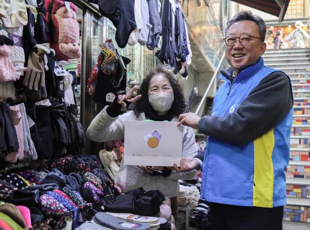 지난 22일 서울시 중구 소재 남대문시장 일대에서 ‘설맞이 상생캠페인’을 진행하고 신한은행 정상혁 은행장이 시장 소상공인에게 선물을 전달하고 기념촬영하는 모습