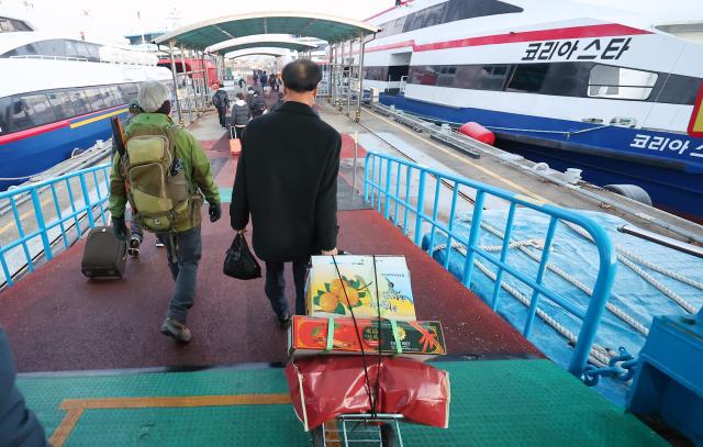 Ahead of the Lunar New Year Holiday homebound passengers on Friday move toward the ferry at the Incheon Port Coastal Passenger Terminal to board Yonhap