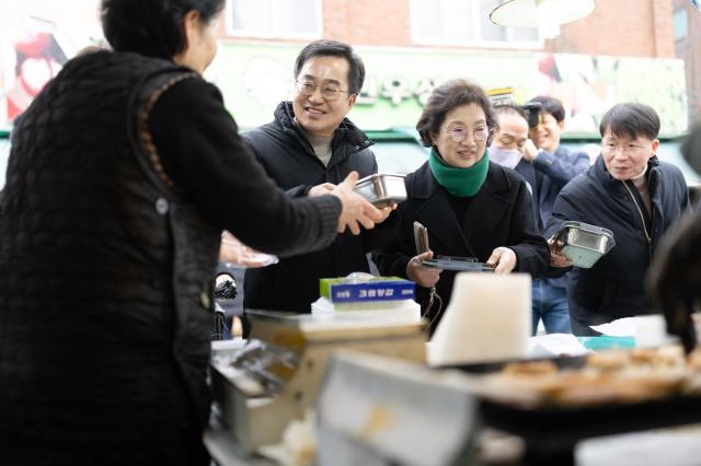  26일 오후 김동연 경기도지사와 정우영 배우자가 설맞이 의왕도깨비시장 방문하여 구매한 전을 다회용기에 포장하고 있다 사진경기도