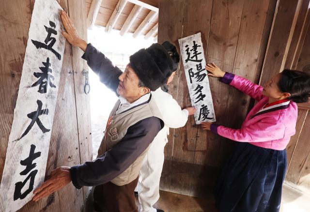 입춘을 하루 앞둔 2일 경기도 용인시 한국민속촌에서 주민들이 입춘첩을 붙이고 있다 YONHAP