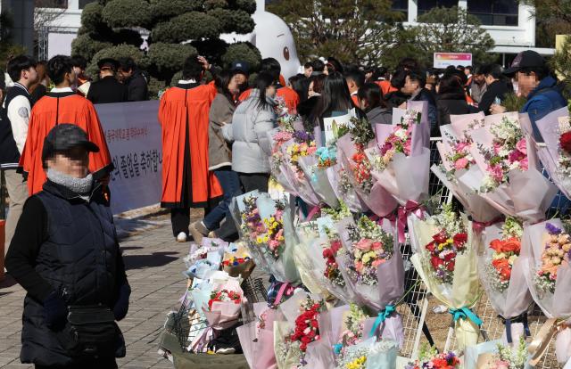 13일 서울 장충동 동국대학교에서 열린 학위수여식
에서 꽃 판매 상인이 고객을 기다리고 있다 경기 악화 속 소비 심리가 위축되면서 졸업식 시즌이지만 꽃다발 특수도 사라졌다 YONHAP

