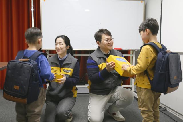 KB국민카드 직원들이 초등학교 입학을 앞둔 아동들에게  책가방을 전달하고 있다 사진KB국민카드