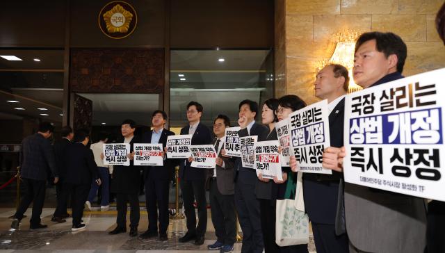 더불어민주당 의원들이 27일 오후 서울 여의도 국회 본회의장 앞에서 상법개정안 상정을 촉구하는 손팻말을 들고 있다 사진연합뉴스