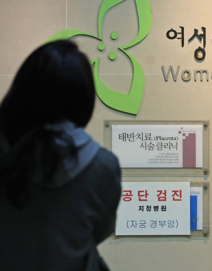 A woman looks at a notice regarding cervical cancer screening posted at an obstetrics and gynecology clinic in Seoul on March 14 2022 Yonhap