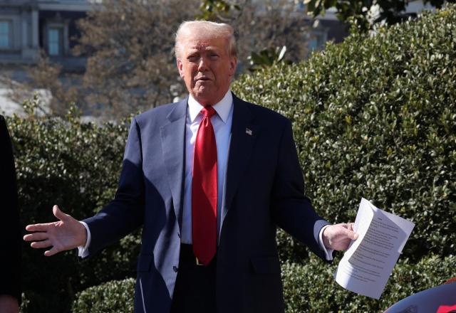 US President Donald Trump poses for a photo holding notes about Tesla cars in front of the White House in Washington March 11 2025 Reuters-Yonhap