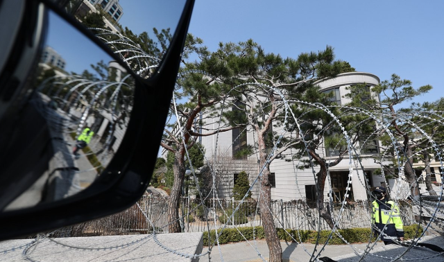 A police officer walks past barbed-wire fencing outside the Constitutional Court of Korea in central Seoul on Mar 14 2025 Yonhap