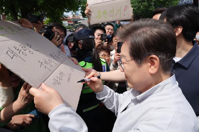 더불어민주당 이재명 대선 후보가 골목골목 경청투어국토종주편에 나선 7일 전북 전주시 풍남문 앞 광장에서 지지자들에게 인사를 하던 도중 한 지지자가 든 공판 연기 환영 대통령은 국민이 뽑습니다라는 팻말에 사인을 하고 있다 이날 서울고등법원은 오는 15일 예정됐던 이 후보의 공직선거법 위반 혐의 사건 파기환송심 첫 공판을 오는 6월 18일로 연기했다 사진연합뉴스
