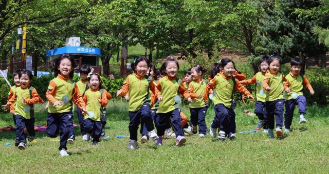Các em học sinh tham gia chuyến đi học ngoài trời đang chạy nhảy vui vẻ tại Công viên Wonjeoksan ở Bupyeong-gu Incheon Hàn Quốc ẢnhYonhap News