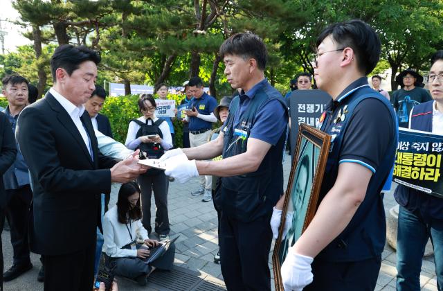 강훈식 대통령비서실장이 6일 서울 용산 대통령실 청사 인근 전쟁기념관 앞에서 태안화력발전소 사고 희생자 고故 김충현 씨와 관련해 엄길용 공공운수노조 위원장 유족 사고 대책위 관계자로부터 요구안 서한을 직접 받고 있다사진연합뉴스
