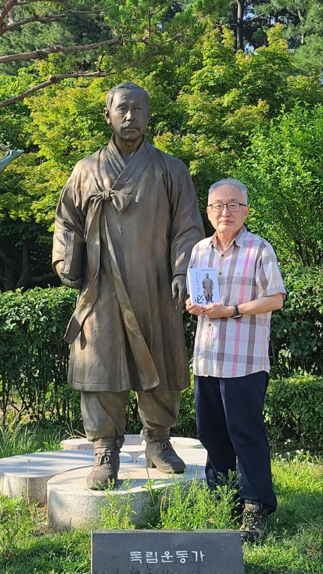 박환 이사장이 수원올림픽공원 필동 임면수 선생 동상에서 ‘필동 임면수 평전’을 헌정한 뒤 기념 촬영을 하고 있다