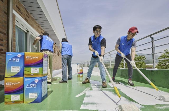 Workers wearing KCC vests coat roof cooling paint Courtesy of KCC 