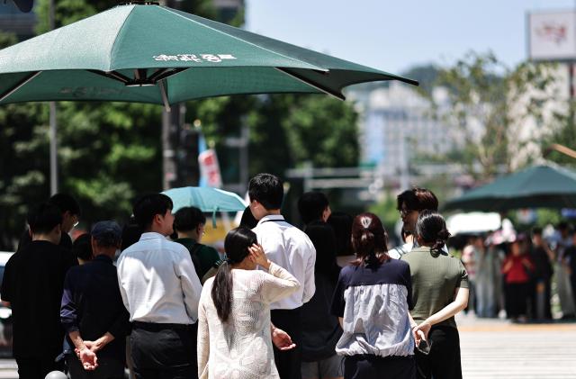무더위가 이어지는 10일 서울 세종로 사거리에서 시민들이 햇빛 가림막 아래에서 신호를 기다리고 있다 사진연합뉴스