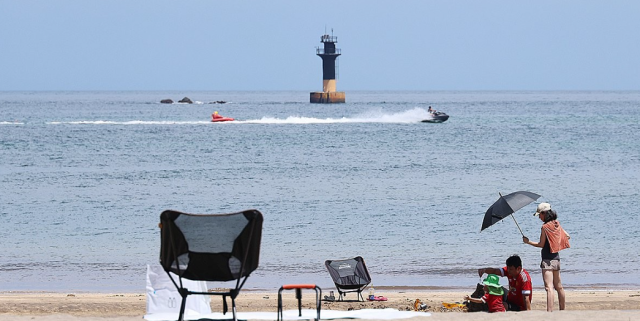 Tourists cool off at a beach in Jeju City South Korea on July 20 2025 Yonhap