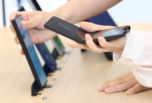 Customers examine foldable smartphones at an electronics store in Seoul South Korea Yonhap